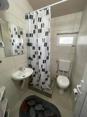 a bathroom with a sink and a toilet and a shower curtain at Maric in Tuzi