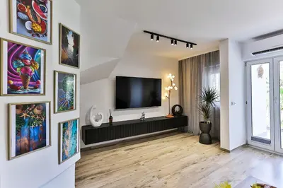 a living room with a television on a wall with pictures at Palm Park Budva in Budva