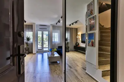 a living room with a staircase and a room with a couch at Palm Park Budva in Budva