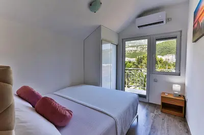 a bedroom with a bed and a large window at Palm Park Budva in Budva