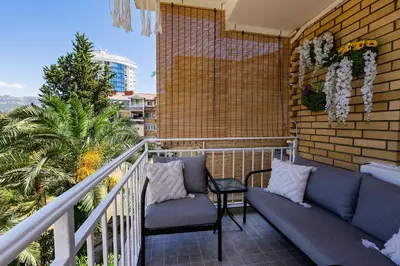 a balcony with a couch and a palm tree at Palm Park Budva in Budva