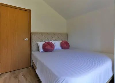 a bedroom with a bed with two red pillows on it at Palm Park Budva in Budva