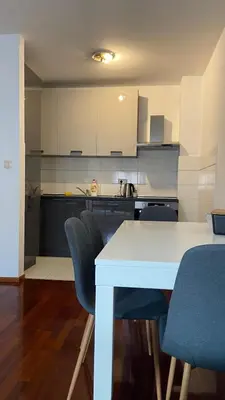 a kitchen with a white table and blue chairs at Cozy city apartment Podgorica in Podgorica