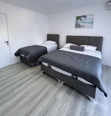 two beds in a room with wooden floors at Harasani apartments in Ulcinj