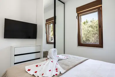 a bedroom with a bed with a dresser and a television at Skyline Residences in Bigovo