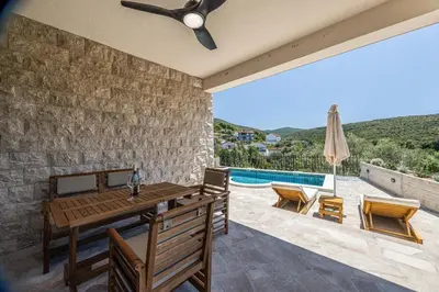 a patio with a table and chairs and a pool at Skyline Residences in Bigovo