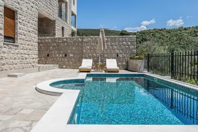 a swimming pool with two chairs next to a house at Skyline Residences in Bigovo