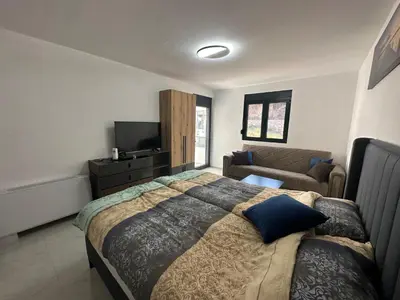 a bedroom with a large bed and a couch at Apartmani Mali Pijesak in Dobra Voda