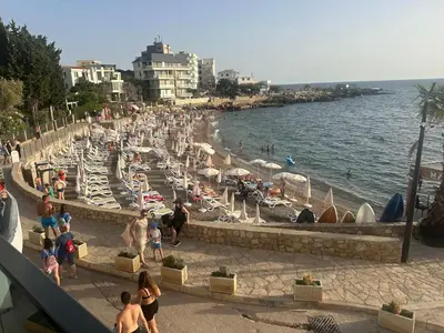 a beach with a crowd of people and the water at Apartmani Mali Pijesak in Dobra Voda