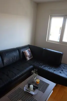 a black leather couch in a living room with a table at Apartment 82 Central Point in Podgorica