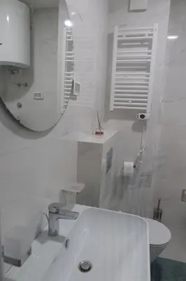 a white bathroom with a sink and a mirror at Apartment 82 Central Point in Podgorica