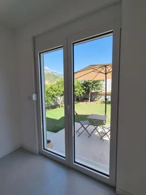 a sliding glass door leading to a patio with an umbrella at Hayal Apartment in Bar