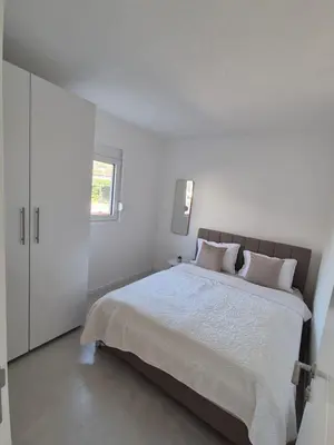 a white bedroom with a large bed and a window at Hayal Apartment in Bar
