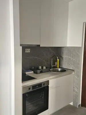 a kitchen with white cabinets and a sink and a stove at Rozino Budva in Budva