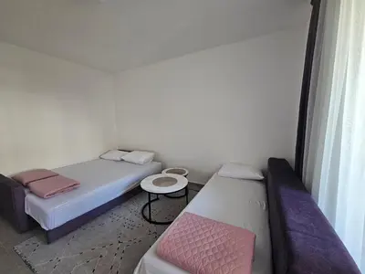 a small room with two beds and a table at Rozino Budva in Budva