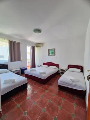 three beds in a room with a red tile floor at Apartments Yll 3 in Ulcinj