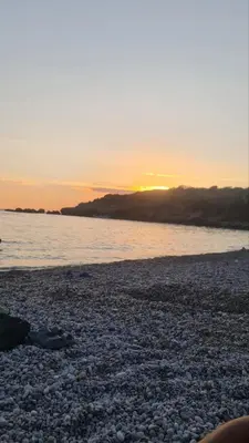 a sunset on a rocky beach with the water at Apartman Martina 3 in Rafailovici