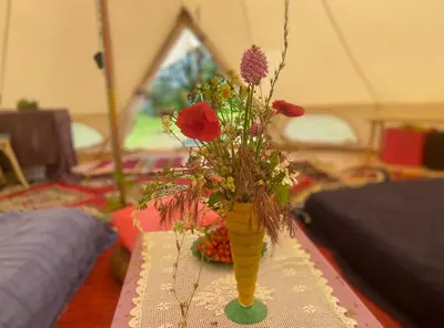a yellow vase filled with flowers on a table at Rudinica Baseglamp in Gornji Brčeli
