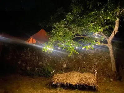 a tent with a tree and a pile of hay at Rudinica Baseglamp in Gornji Brčeli