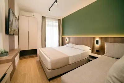 a bedroom with a white bed and a green wall at Solea Apartments in Ulcinj