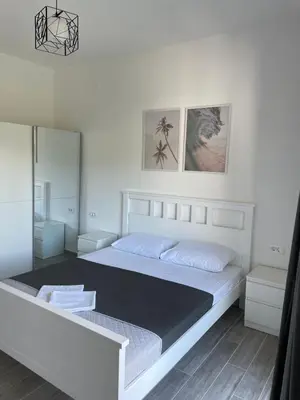 a white bedroom with a large bed and a mirror at Quattro Rocce Apartments Zelen in Sutomore