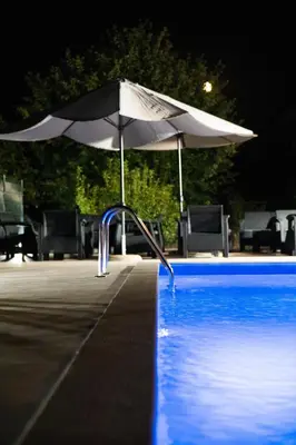 a white umbrella next to a swimming pool at night at Blue Escape in Danilovgrad