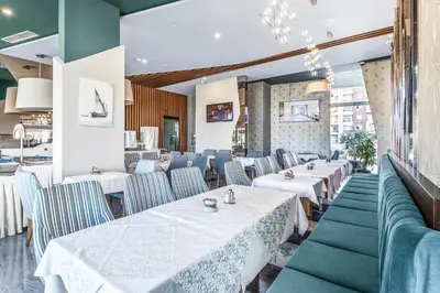 a restaurant with white tables and blue chairs at Hotel Bracera in Budva