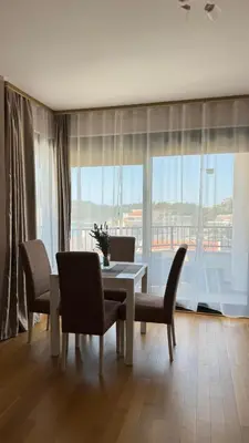 a dining room with a table and chairs and a large window at One bedroom apartment with sea view Becici in Becici
