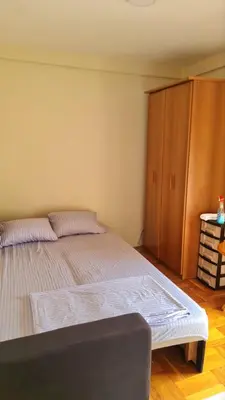 a bedroom with a large bed and a wooden cabinet at Apartman braco in Budva