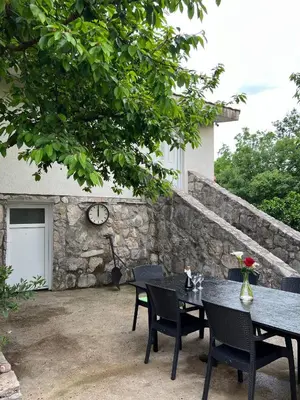 a patio with a table and chairs and a clock at Nina House Charming Apartment, Prevlaka in Prevlaka