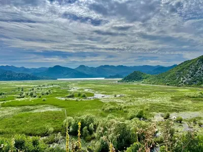 a field with a river and mountains in the background at Nina House Charming Apartment, Prevlaka in Prevlaka