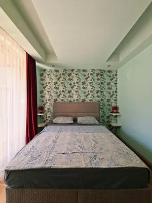 a bedroom with a large bed with floral wallpaper at Cozy City Center Studio in Babalonija