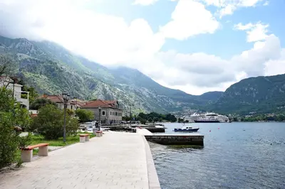a walkway next to a body of water with mountains at Apartments Martiva in Kotor