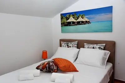 a bedroom with a bed with white sheets and a painting on the wall at Apartments Martiva in Kotor