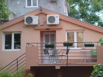 a pink house with two air conditioners on a balcony at Apartments Martiva in Kotor