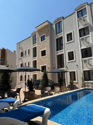 a pool with chairs and umbrellas next to some buildings at Apartment with balcony sea view and Parking B12 in Budva