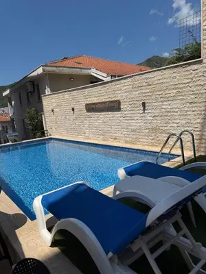 a blue swimming pool with two chairs next to a building at Apartment with balcony sea view and Parking B12 in Budva