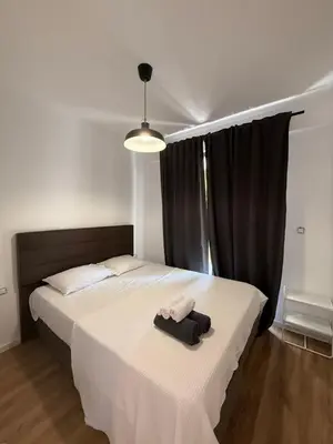 a bedroom with a white bed with a black curtain at Apartment with balcony sea view and Parking B12 in Budva