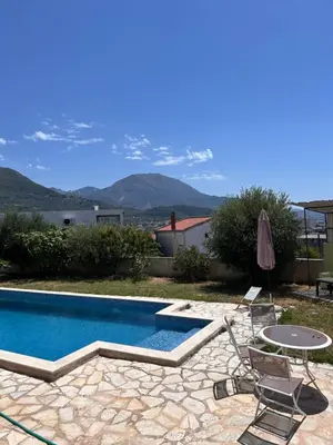 a swimming pool with chairs and a table and an umbrella at Villa Alidah Avkoppling med utsikt, pool och fruktträd in Bar