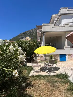 a yellow umbrella and chairs in front of a house at Villa Alidah Avkoppling med utsikt, pool och fruktträd in Bar