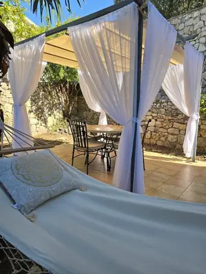 a hammock in front of a patio with a table at Vista Blue Villa in Budva