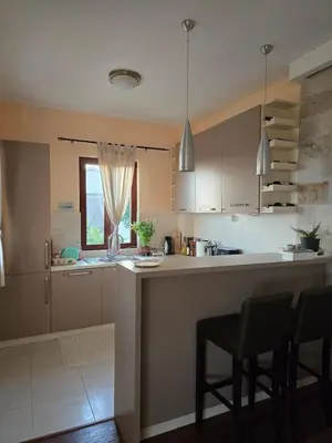 a kitchen with white cabinets and a counter with chairs at Vista Blue Villa in Budva