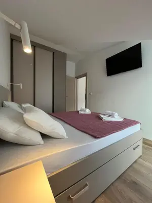 a bedroom with a large bed with a tv on the wall at Petra & Vuk Apartments Kotor in Kotor