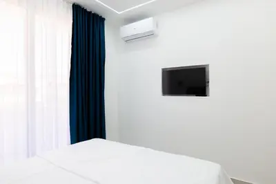 a bedroom with a white bed and a tv at Diamonds Xh&A Apartments in Ulcinj