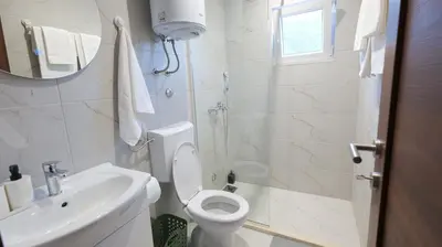 a white bathroom with a toilet and a sink at Riječki grad Apartments in Rijeka Crnojevića