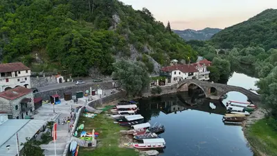 a bridge over a river in a town with boats at Riječki grad Apartments in Rijeka Crnojevića