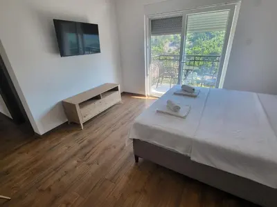 a bedroom with a bed and a television and a balcony at Riječki grad Apartments in Rijeka Crnojevića