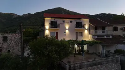 a white house with a mountain in the background at Riječki grad Apartments in Rijeka Crnojevića