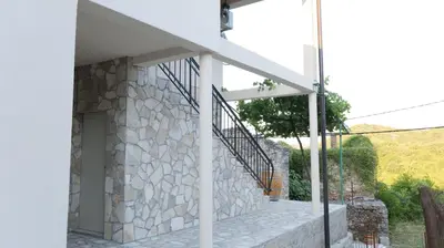 a house with a stone wall and a staircase at Riječki grad Apartments in Rijeka Crnojevića