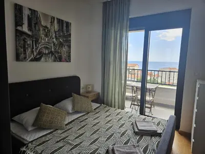 a bedroom with a bed and a view of a balcony at Apartament Onyx in Becici